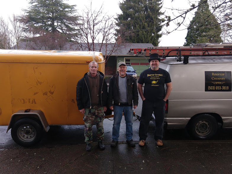 Three men standing between service vehicles outdoors.