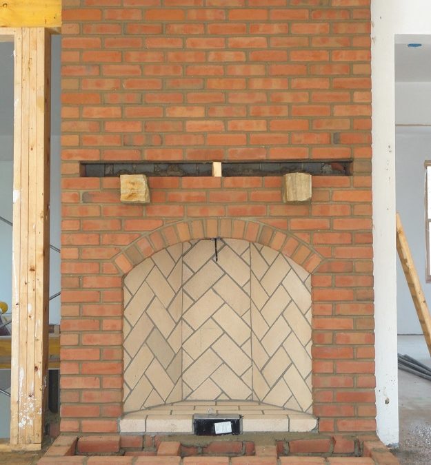 Brick fireplace under construction with herringbone pattern.