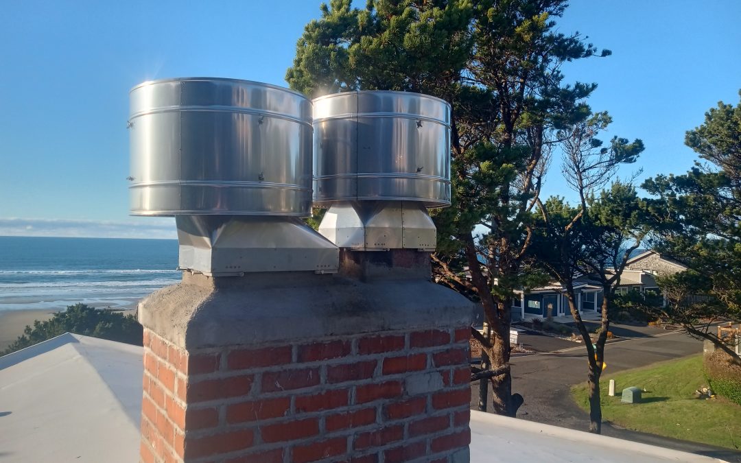 Stainless steel Monsoon rain caps installed on a chimney in Newport, Oregon. No rain can blow into the caps. Caps prevent wind downdrafts.
